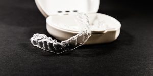 Clear, virtually invisible Invisalign aligners set against their case.