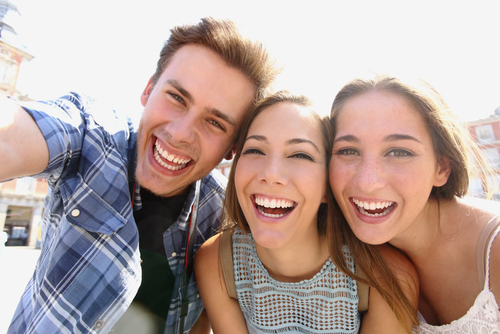 a teen guy and two teen girls smiling and taking a selfie